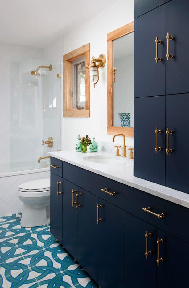 a bathroom with navy blue cabinets and brass hardware