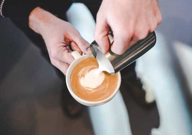 Barista pouring milk into a cappuccino