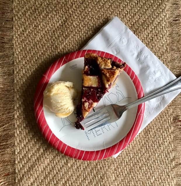 triple berry pie slice on a plate with ice cream and fork