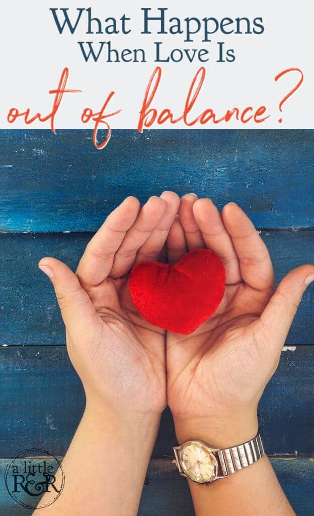 person with watch holding red heart against blue wood background