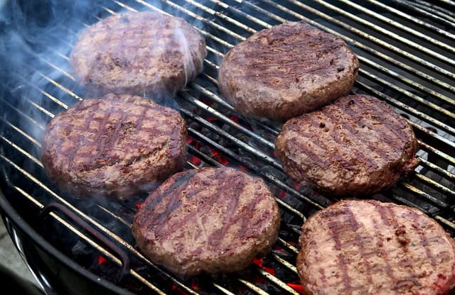 Gourmet beef steak burgers sizzling on a BBQ