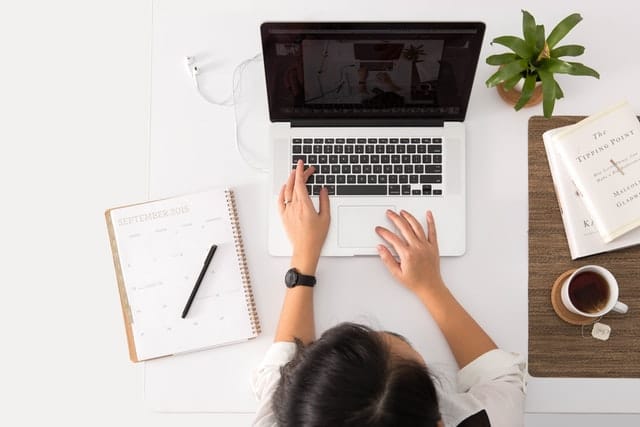 Overhead shot of a woman typing on a laptop.