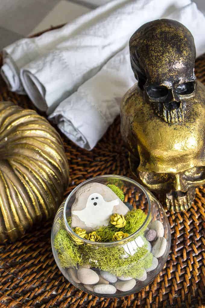 painted ghost rock in terrarium Halloween terrarium on display with gold skull decor