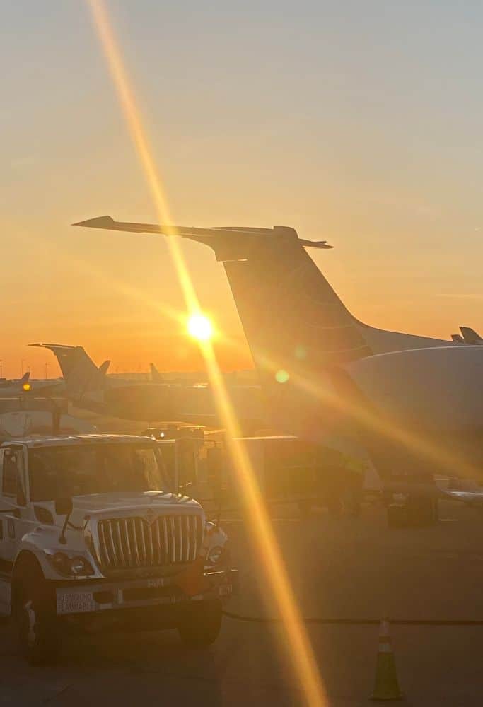The Lisbon sunset seen under the tail of an airplane on the tarmac.