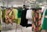Clothing racks in a store display with green and floral dresses on hangers.