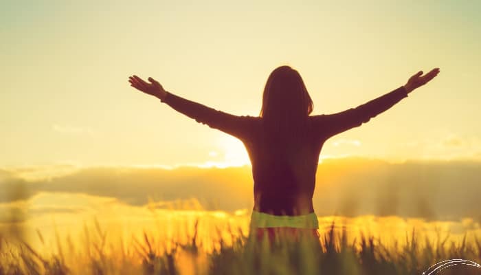 Woman in field with hands raised