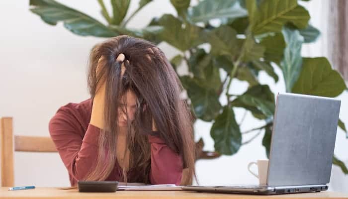 woman sitting at laptop with head in her hands
