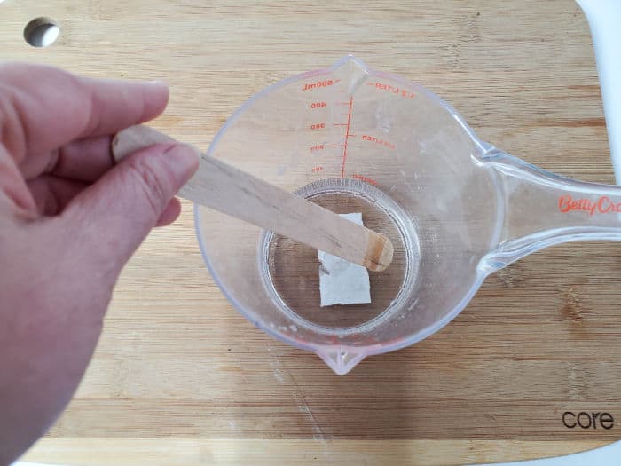 Mixing the ingredients in a measuring cup with a wooden stir stick.