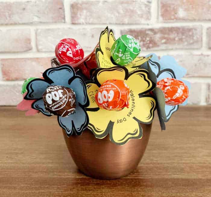 lollipop bouquet on a wood table with brick wall in the background.