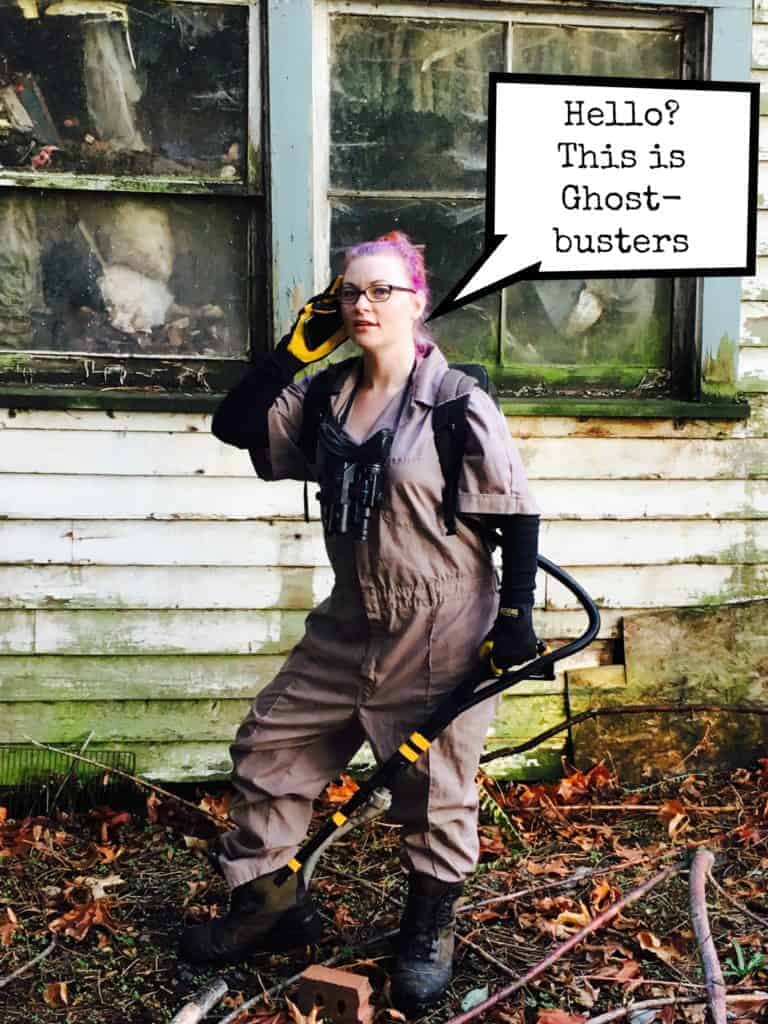 Woman in ghostbuster costume holding phone and gun