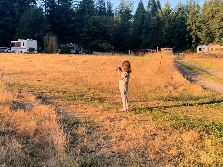 young girl playing with camera in a field