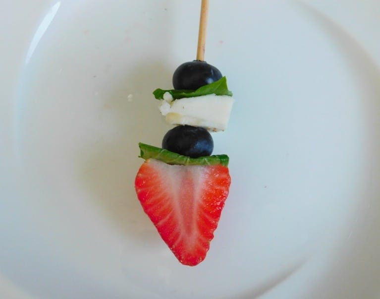 Strawberry on a wood skewer with blueberries, cheese and basil.