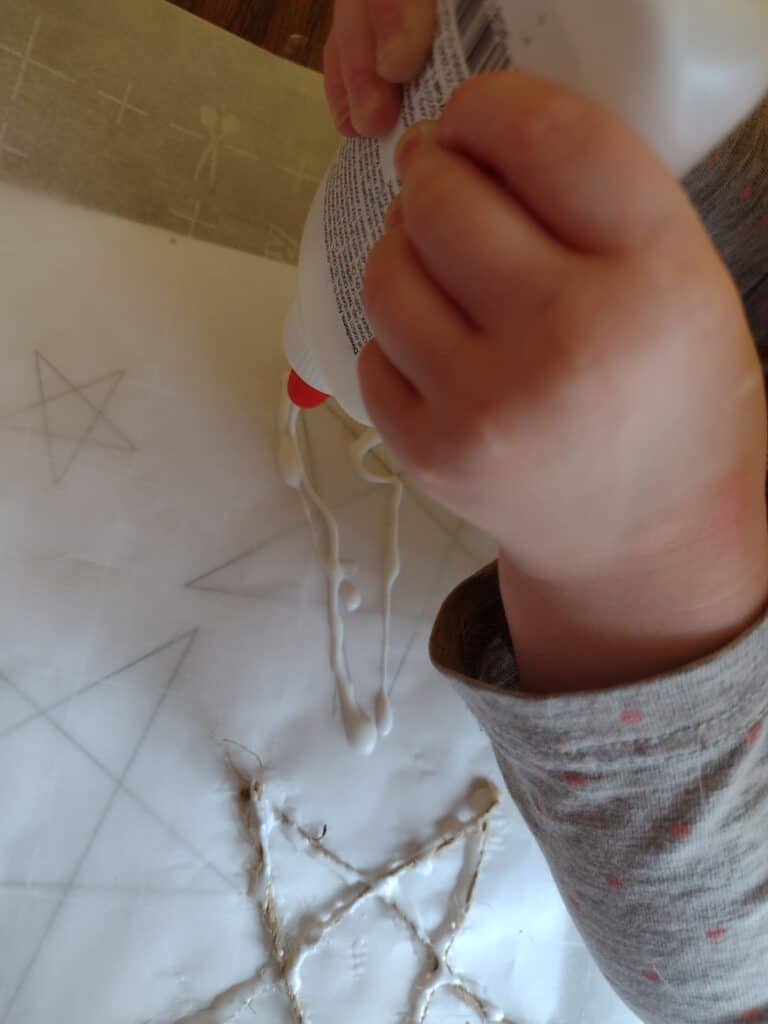 Picture of a preschooler gluing around a star