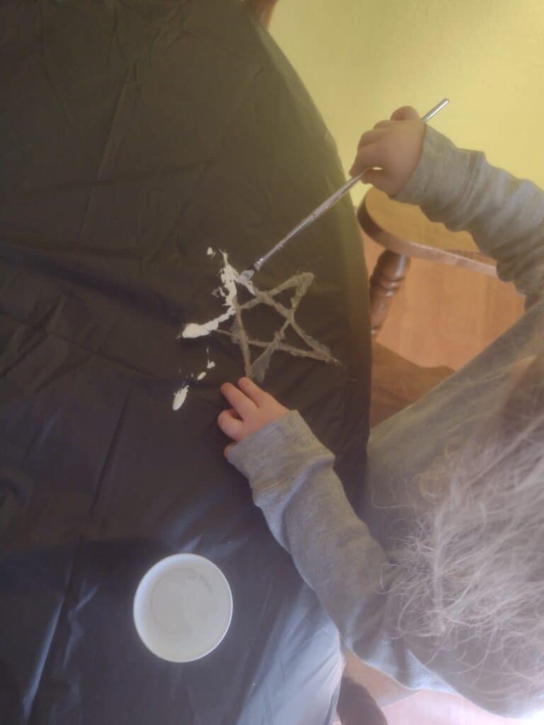 Picture of a preschooler painting a twine star white