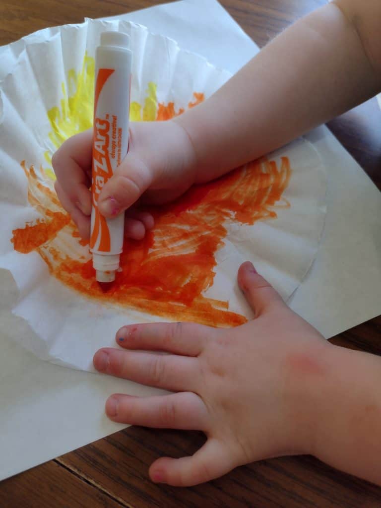 Picture of a preschooler coloring a coffee filter red, orange, and yellow
