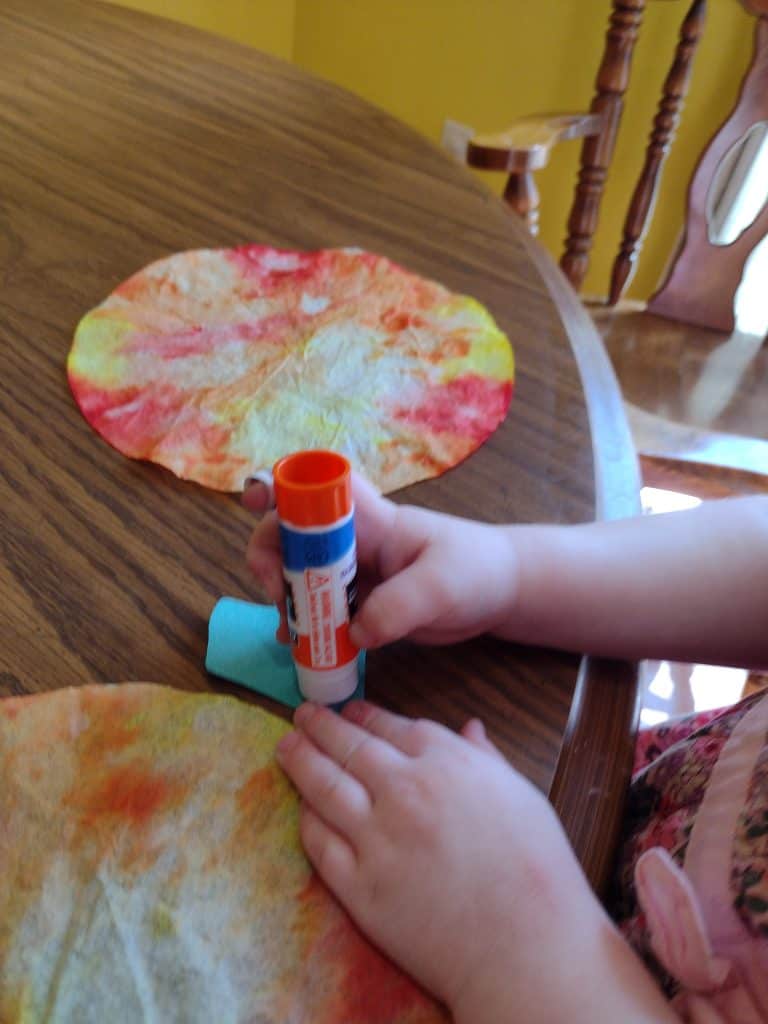Picture of a preschooler putting glue on a construction paper stem