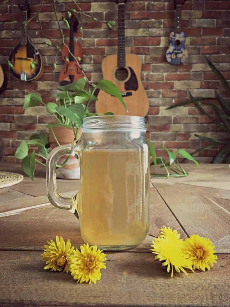 dandelion root tea in mug on table with dandelion flowers