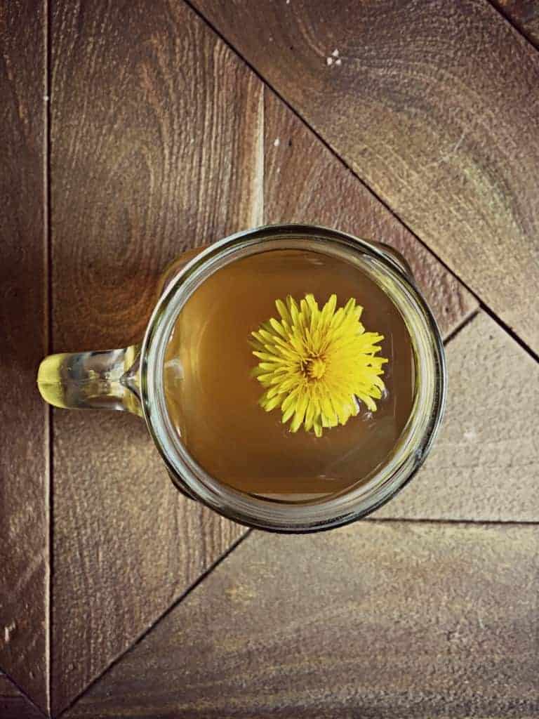 dandelion root tea in cup with yellow flower