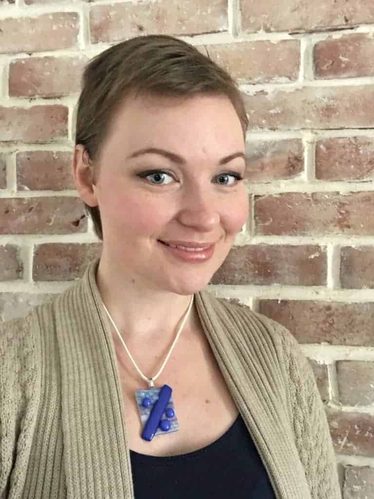 Girl with short brown hair in front of brick wall.