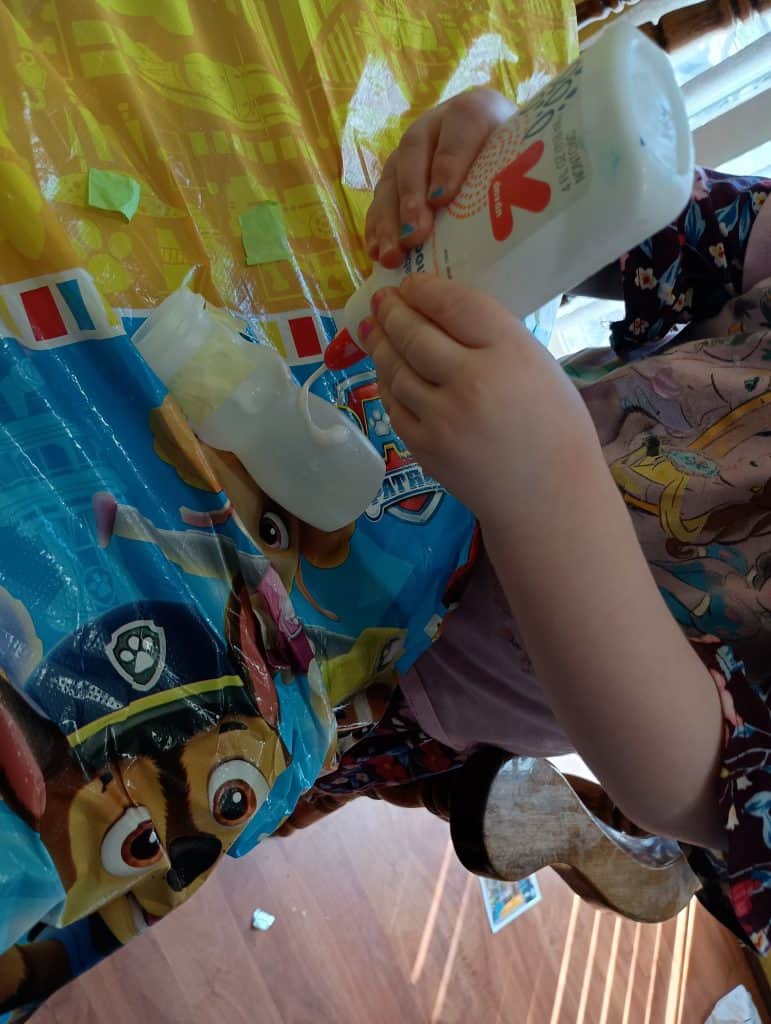 Picture of a preschooler squeezing glue on a Danimals container