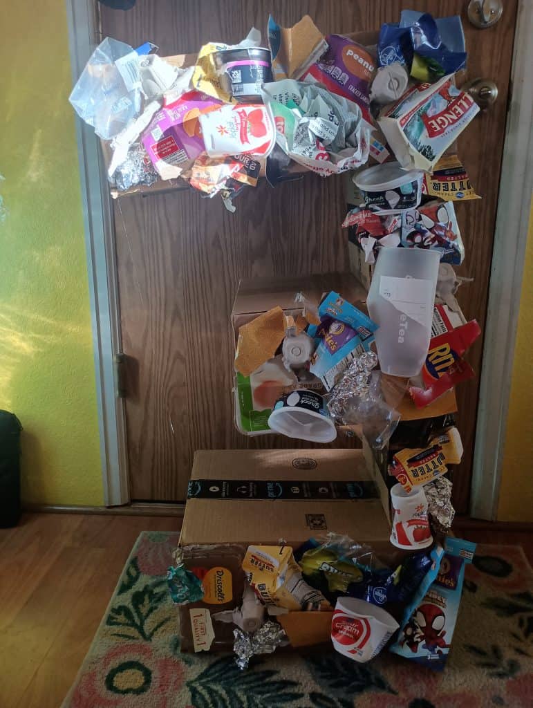 Picture of large number 3 made of carboard boxes and covered in trash