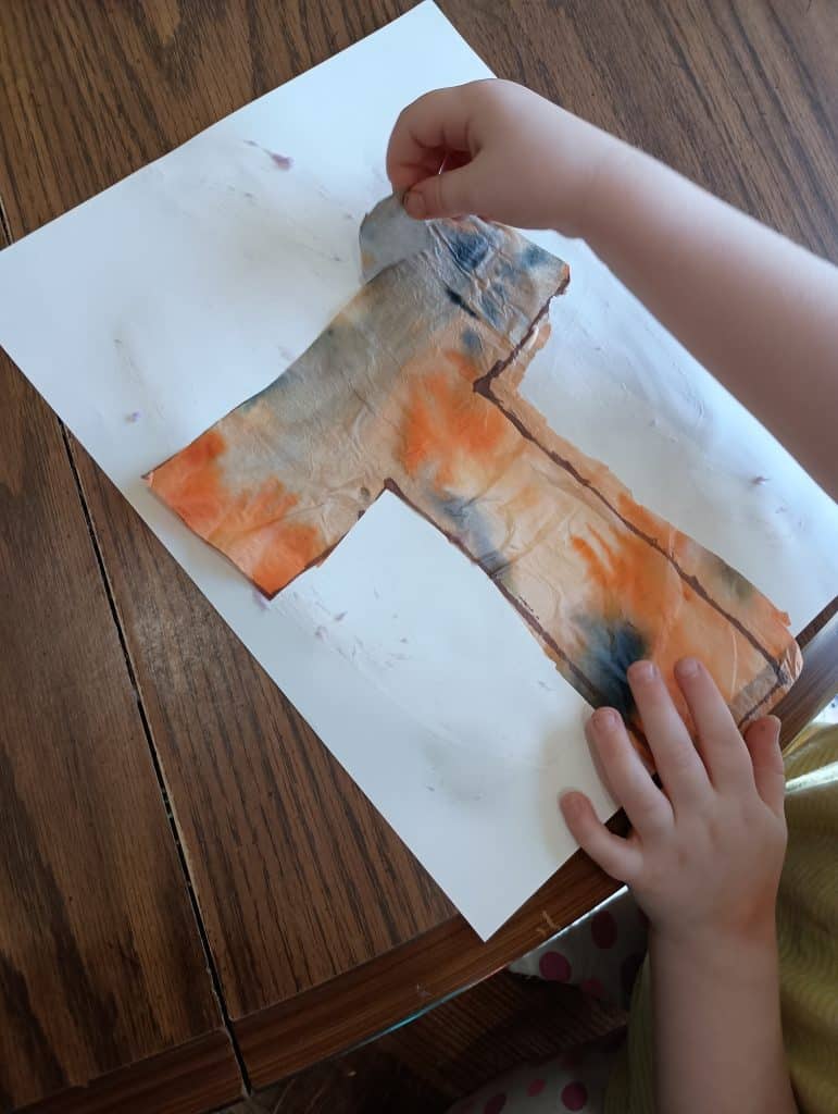 Picture of a preschooler gluing a tissue paper tiger ear to a T is for tiger craft