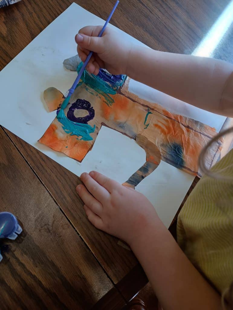 Picture of a preschooler painting eyes on a T is for tiger craft