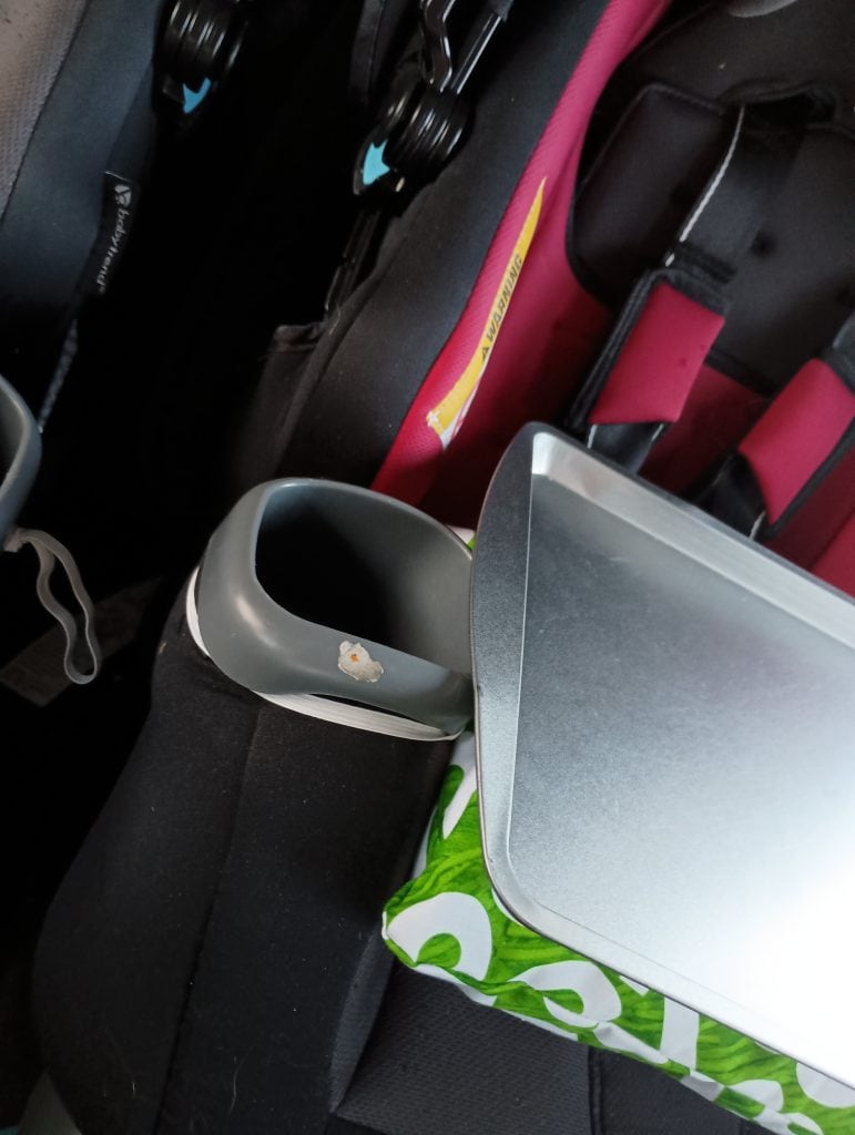 Picture of a homemade car seat tray attached to a cupholder using elastic