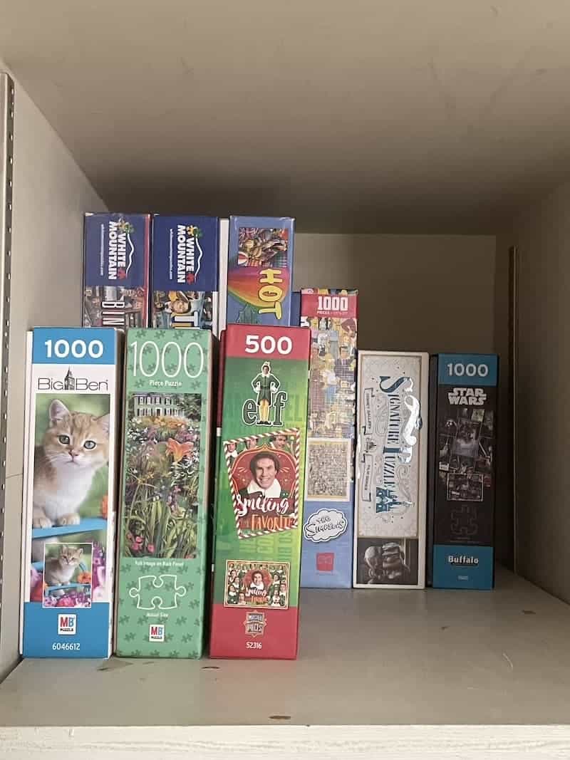 puzzle boxes standing on their ends on a shelf in a closet