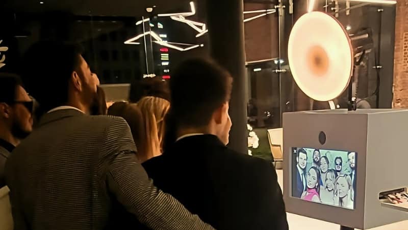 Goście stojący przy ekranie samoobsługowej fotobudki podczas wieczornego eventu