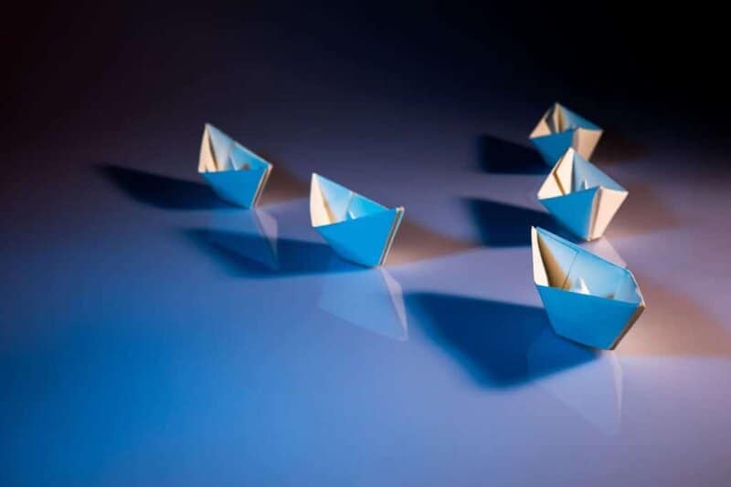 A fleet of paper boats. One leading at the front.