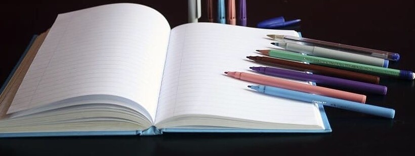 An open notebook with different types of pens
