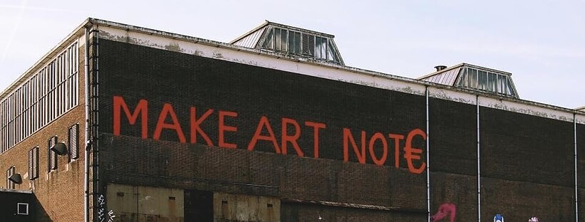 A warehouse building with 'make art not €' painted on it