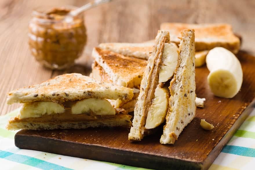 Peanut butter and banana sandwiches cut into triangles on a cutting board