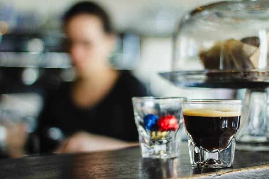 Long espresso on a bar with a barista in the background