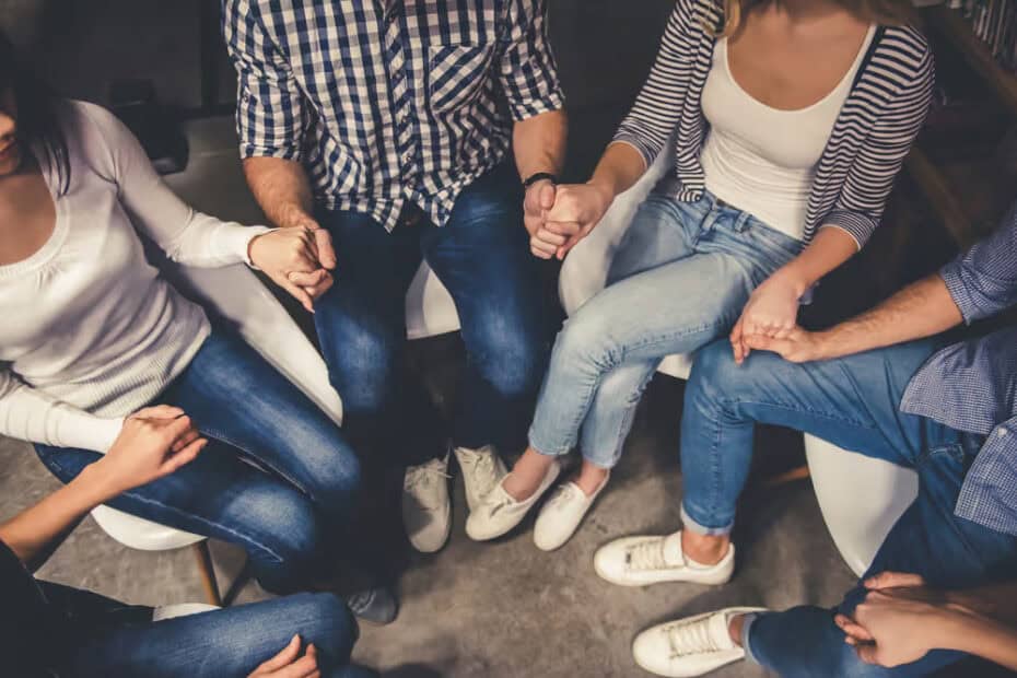 Addiction support group holding hands during meeting