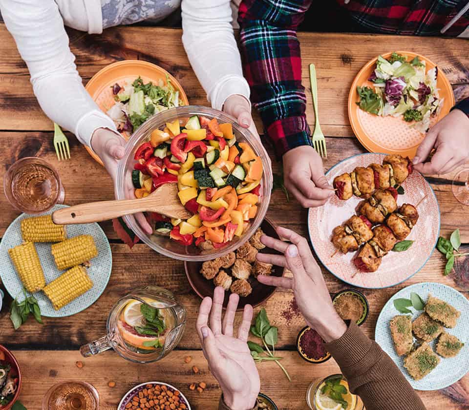 table top with vegan food and hands sharing and passing