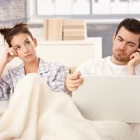 Disinterested couple sitting on couch.
