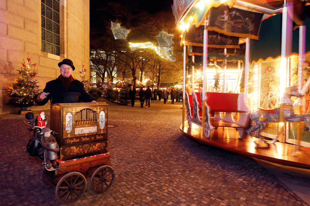 Uriges Flair am Weihnachtsmarkt am Opernpalais mit einem Leierkastenspieler vor dem nostalgischen 1_Kinderkarussell_Copyright Agentur DAVIDS (1)