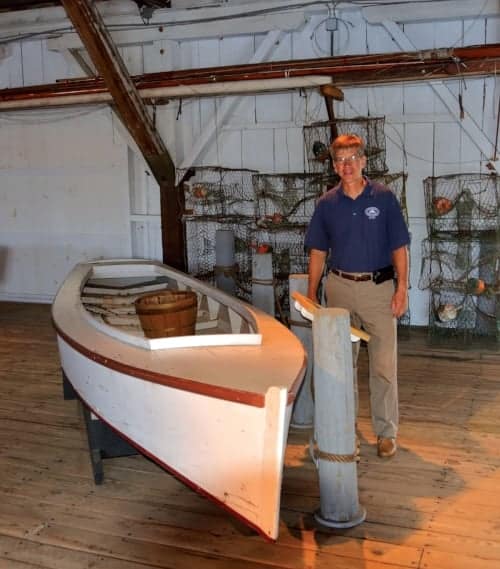 Chesapeake Bay Maritime Museum chief curator Pete Lesher stands beside an original Smith Island crab skiff in the museum’s small boat collection. Photo by Dick Cooper.