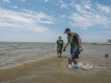 Juan Garzon and Ali Rezaie, doctoral students in coastal engineering at George Mason University, search the shallows for a submerged wave sensor they had planted on the bottom weeks earlier. (Dave Harp)