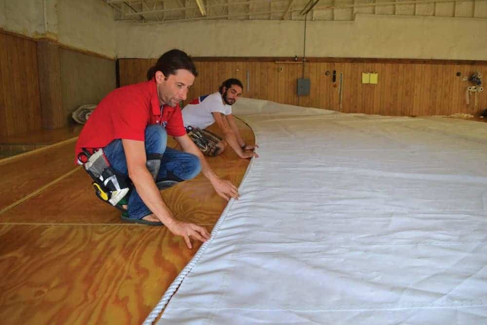 Sailmakers Ailsworth and Jake Pender lay out a sail’s bolt-rope. Photo by Karen Soule.