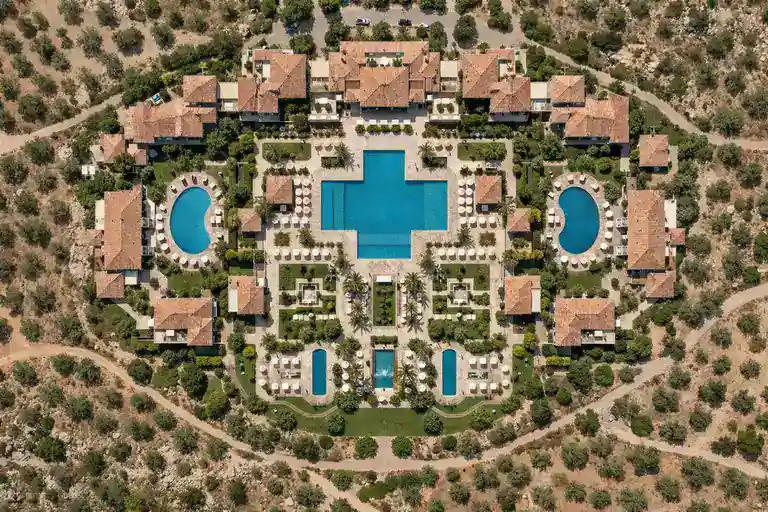 Fotografía aérea cenital de resort de lujo con piscinas y jardines visto perpendicularmente desde arriba en luz técnica de mediodía