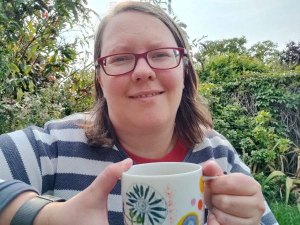 Rachel Extance holding a cup of coffee, sitting in her garden