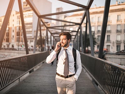 Business Man Using Mobile Integration to Talk on Cell Phone While Crossing Bridge