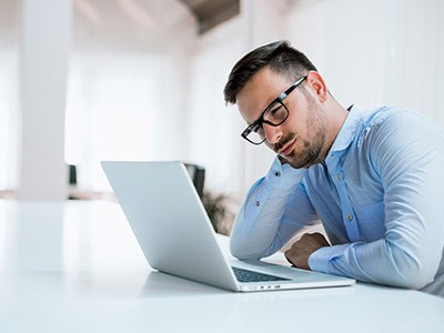 Confused business man searching for a new business phone service provider on laptop