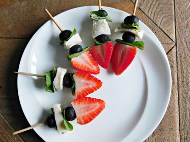 fruit kabobs on white plate and wooden tabletop