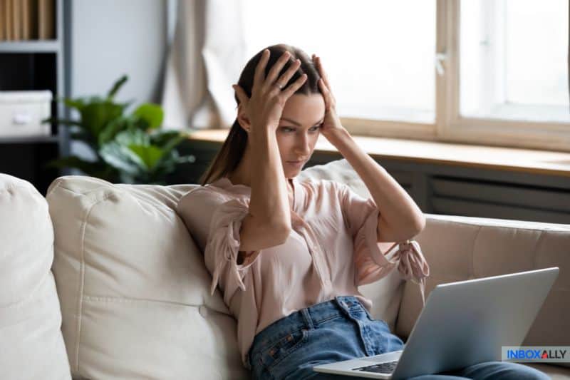 Uma mulher frustrada olhando para seu laptop, tentando resolver o problema de 