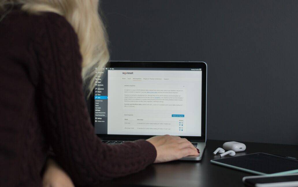 A woman using a laptop on a desk for WordPress emails.