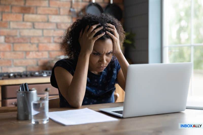 Frustrated woman looking at laptop, struggling with Mailchimp emails going to spam, searching for solutions to fix email deliverability issues